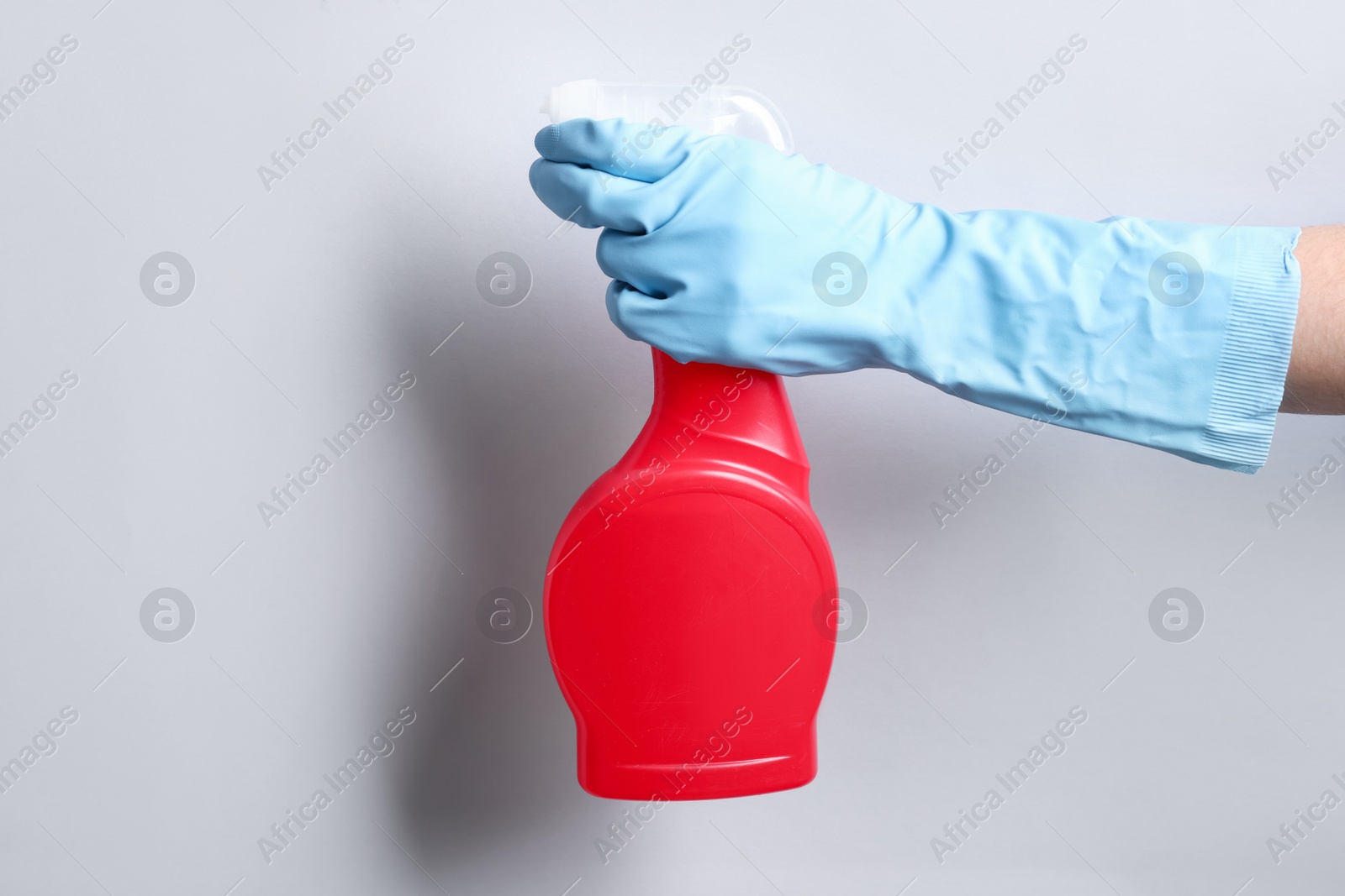 Photo of Woman with spray bottle of cleaning product on light grey background, closeup. Space for text