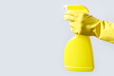 Photo of Woman with spray bottle of cleaning product on light grey background, closeup. Space for text