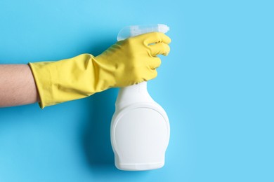 Photo of Woman with spray bottle of cleaning product on light blue background, closeup