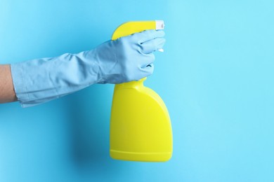 Photo of Woman with spray bottle of cleaning product on light blue background, closeup