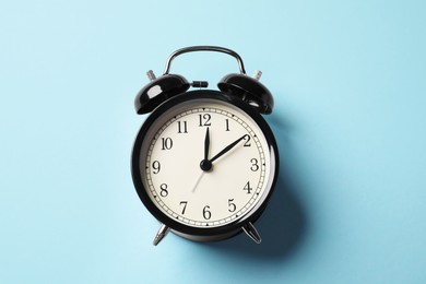 Photo of Black alarm clock on light blue background, top view