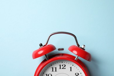 Photo of Red alarm clock on light blue background, top view. Space for text