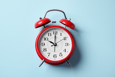 Photo of Red alarm clock on light blue background, top view