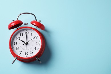 Photo of Red alarm clock on light blue background, top view. Space for text