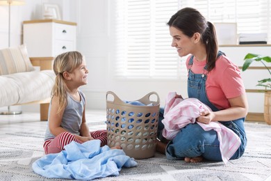 Photo of Little helper. Daughter and her mother with laundry at home