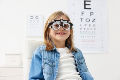 Photo of Vision testing. Little girl with trial frame at ophthalmologist office