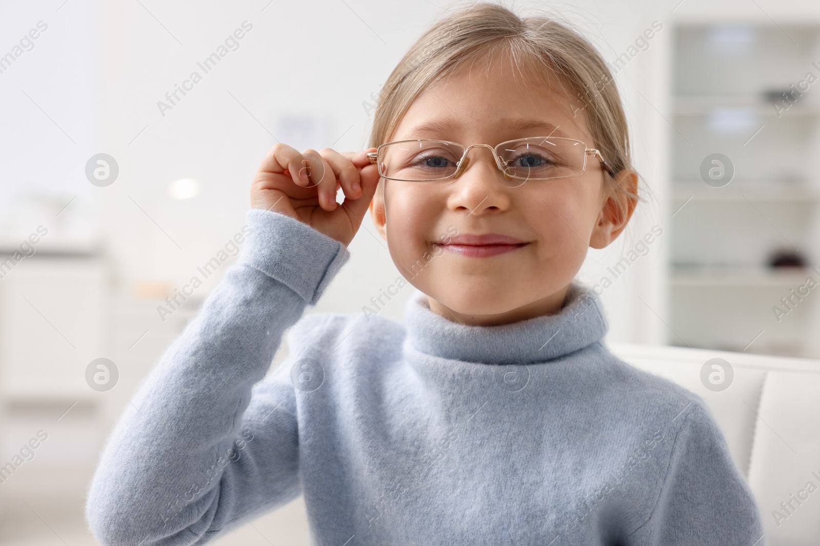 Photo of Little girl trying glasses at ophthalmologist office