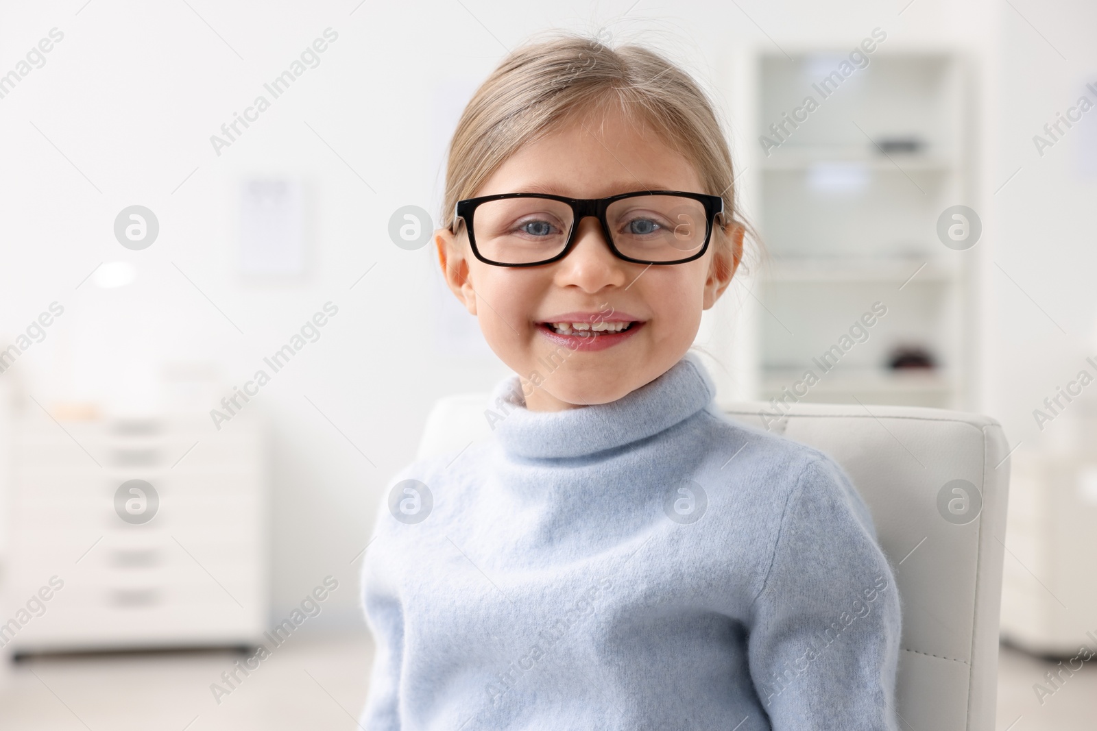 Photo of Little girl trying glasses at ophthalmologist office