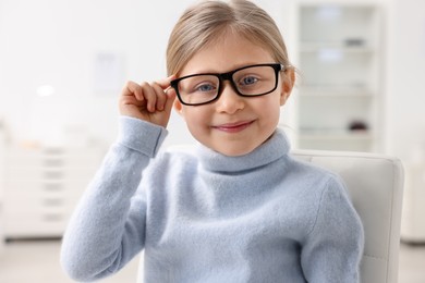 Photo of Little girl trying glasses at ophthalmologist office