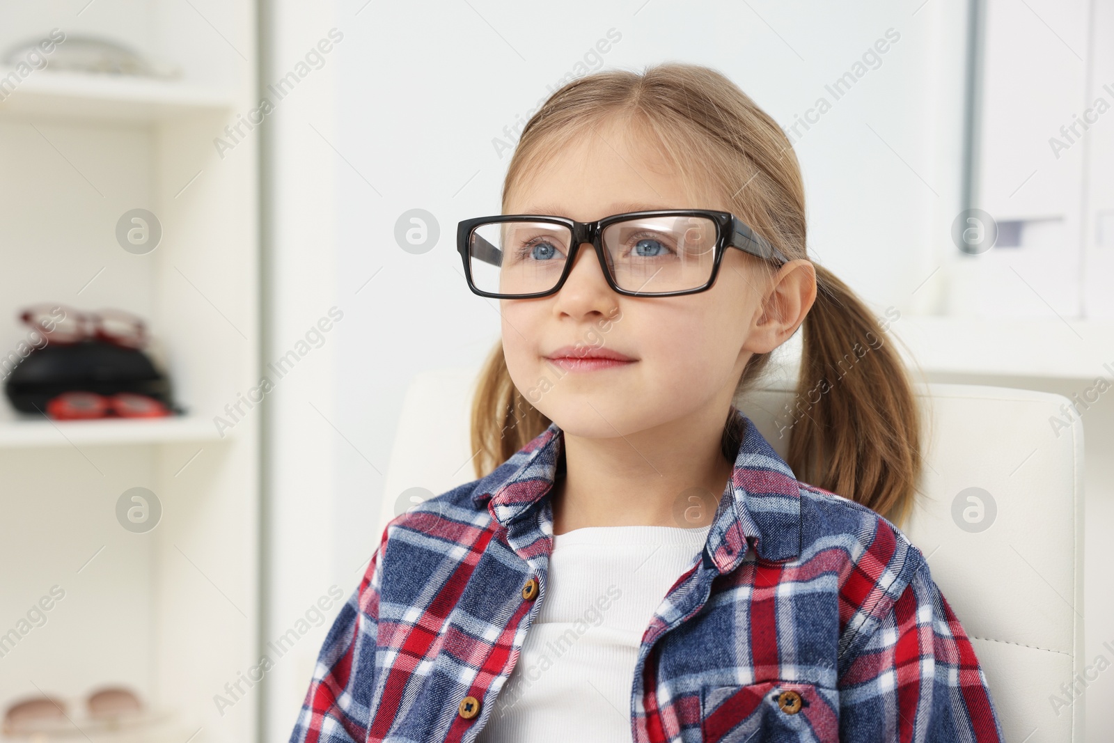 Photo of Little girl trying glasses at ophthalmologist office