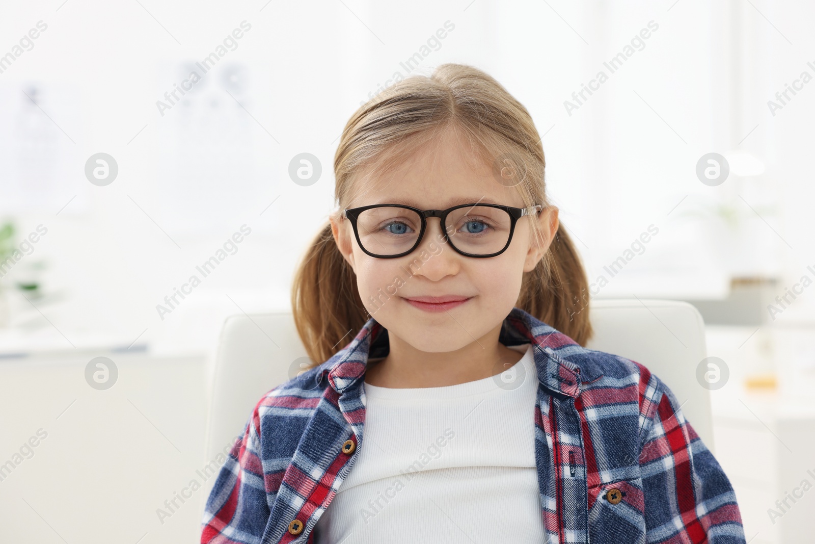 Photo of Little girl trying glasses at ophthalmologist office