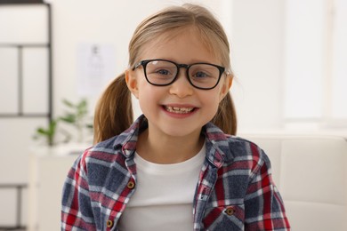 Photo of Little girl trying glasses at ophthalmologist office