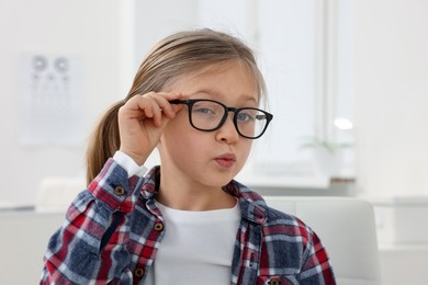 Photo of Little girl trying glasses at ophthalmologist office