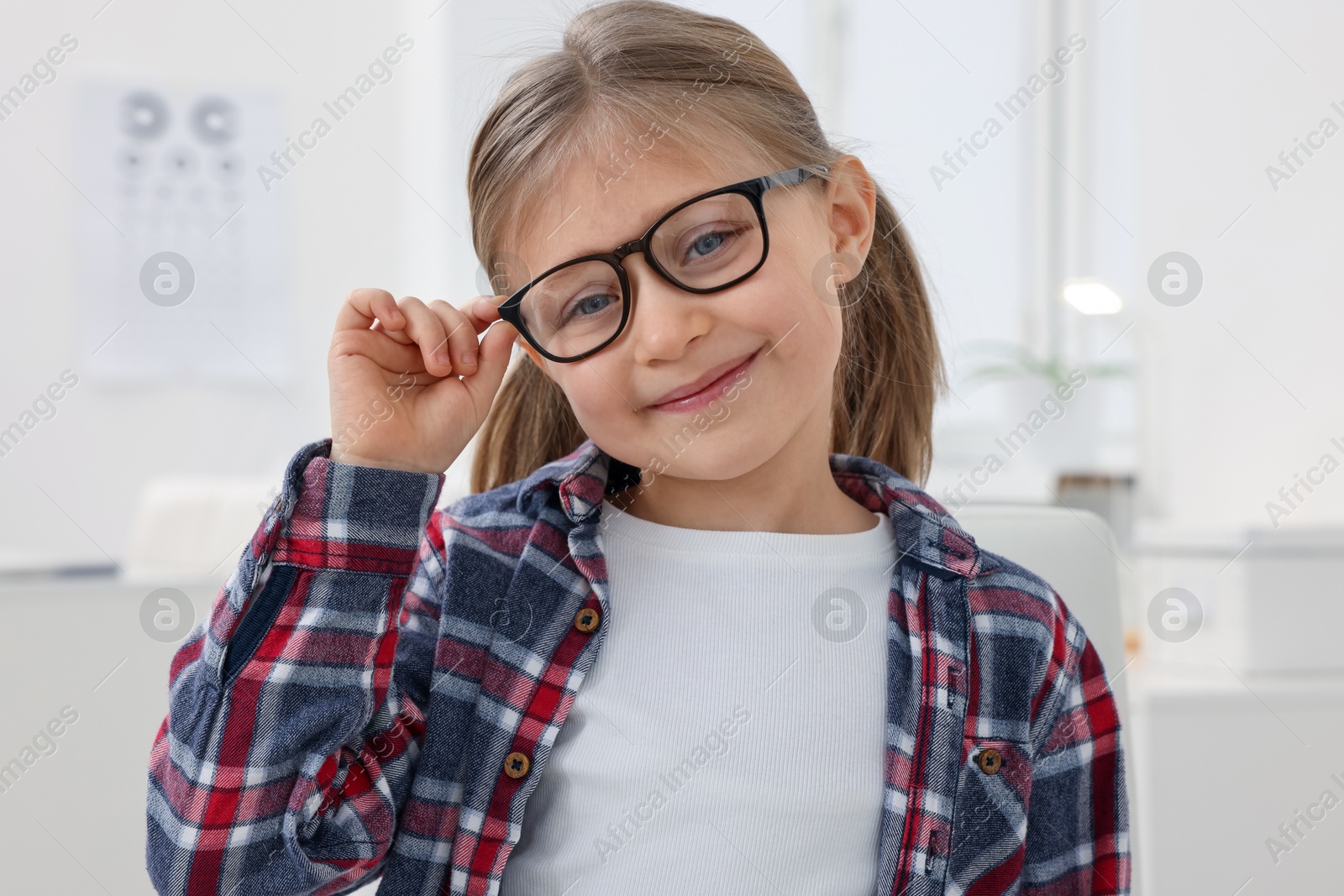 Photo of Little girl trying glasses at ophthalmologist office