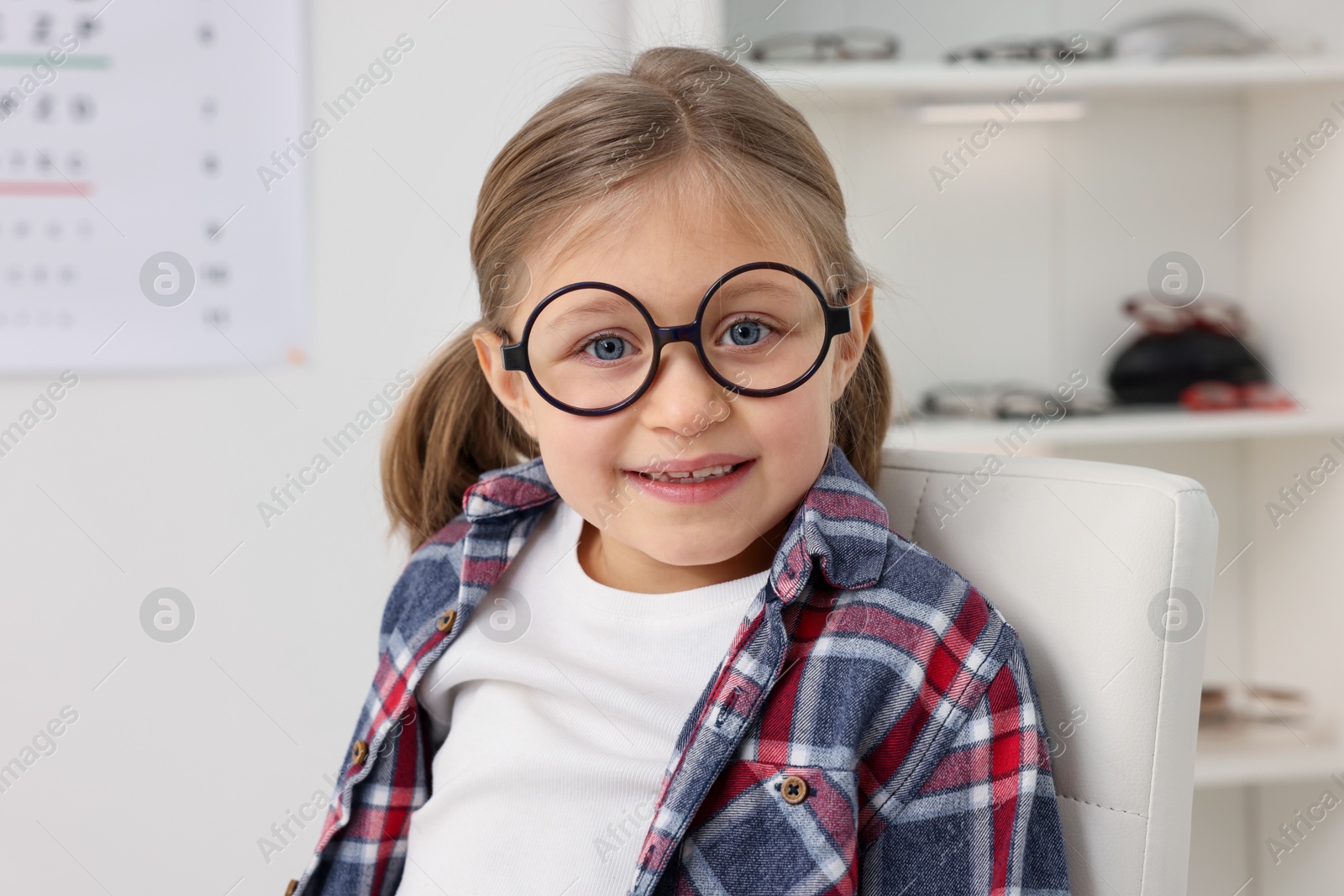 Photo of Little girl trying glasses at ophthalmologist office