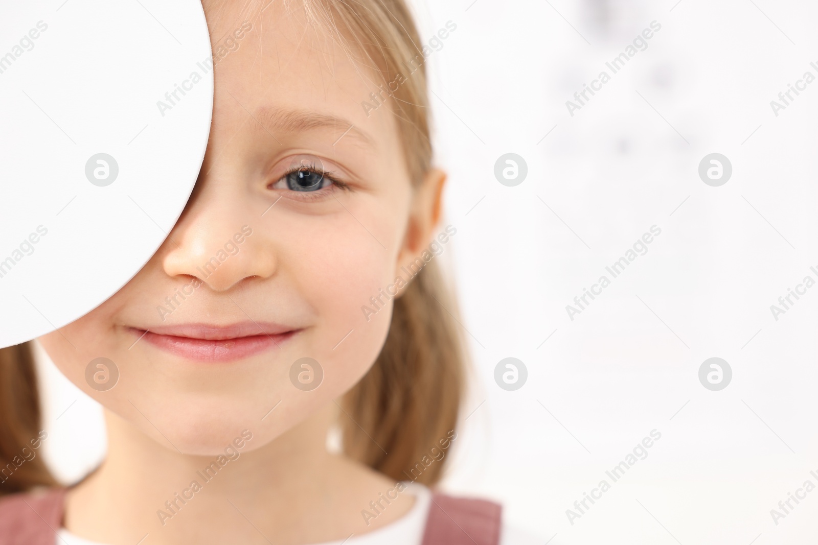 Photo of Little girl covering her eye at ophthalmologist office, space for text