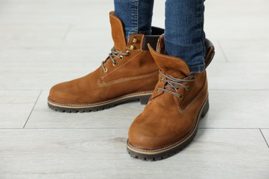 Photo of Child wearing oversized brown boots indoors, closeup