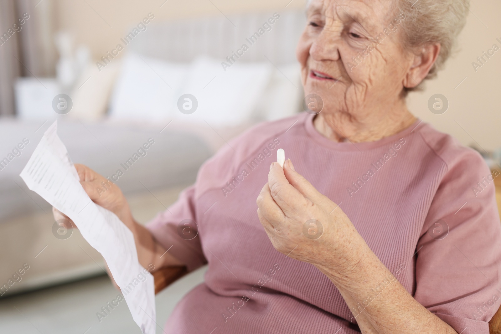 Photo of Senior woman with medical instruction and pill at home, selective focus