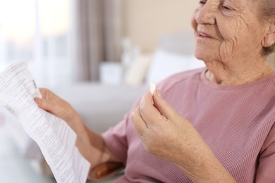 Senior woman with medical instruction and pill at home, selective focus