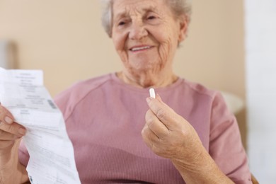 Photo of Senior woman with medical instruction and pill at home, selective focus