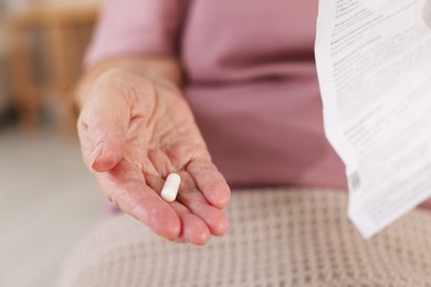 Photo of Senior woman with medical instruction and pill, closeup