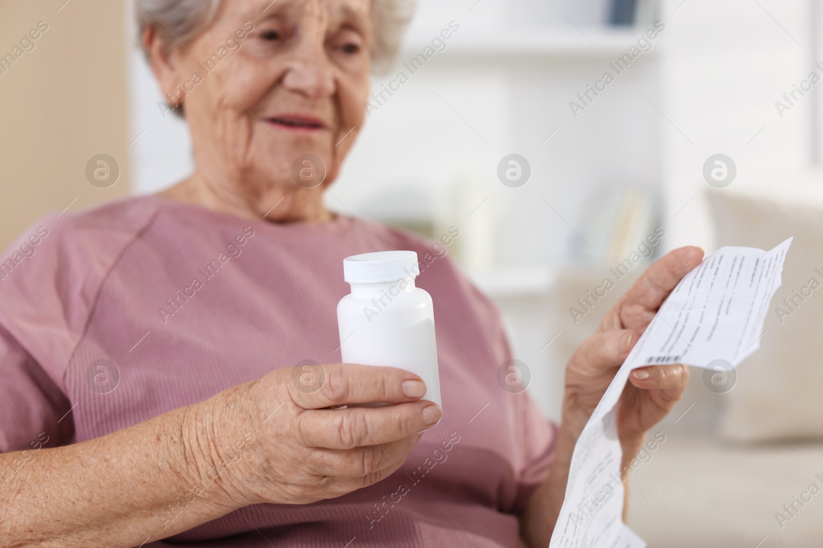 Photo of Senior woman with medical instruction and bottle of pills at home, selective focus