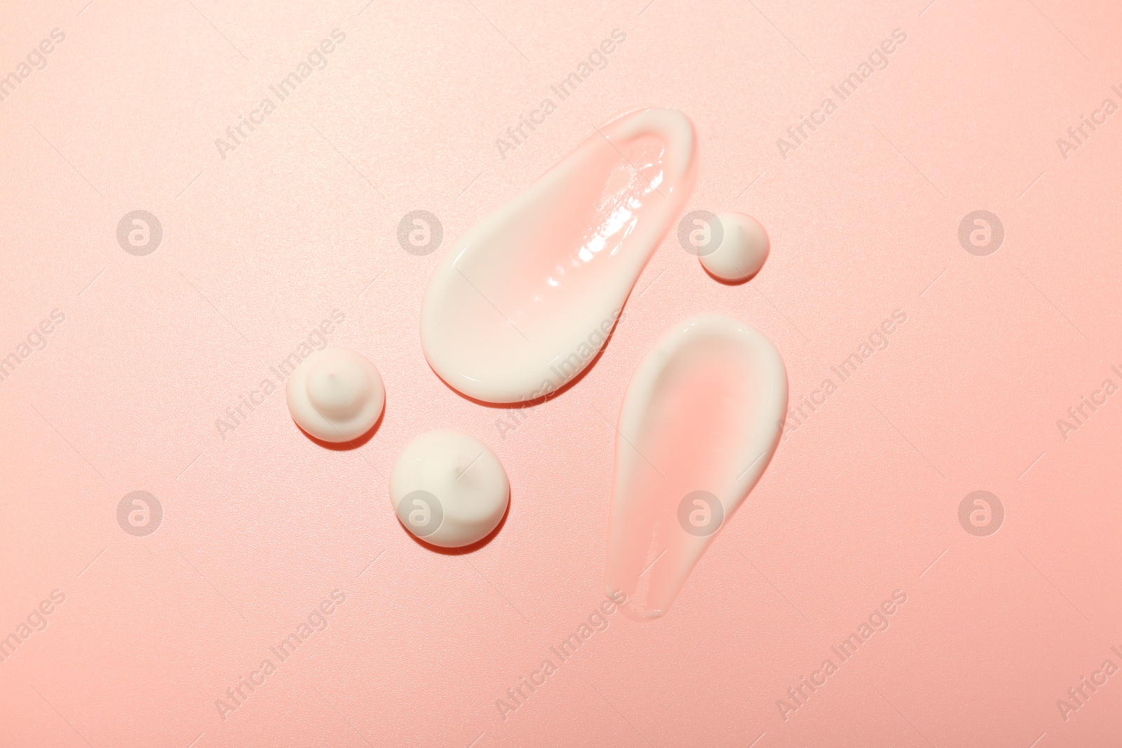 Photo of Cream samples on pink background, top view. Skincare product