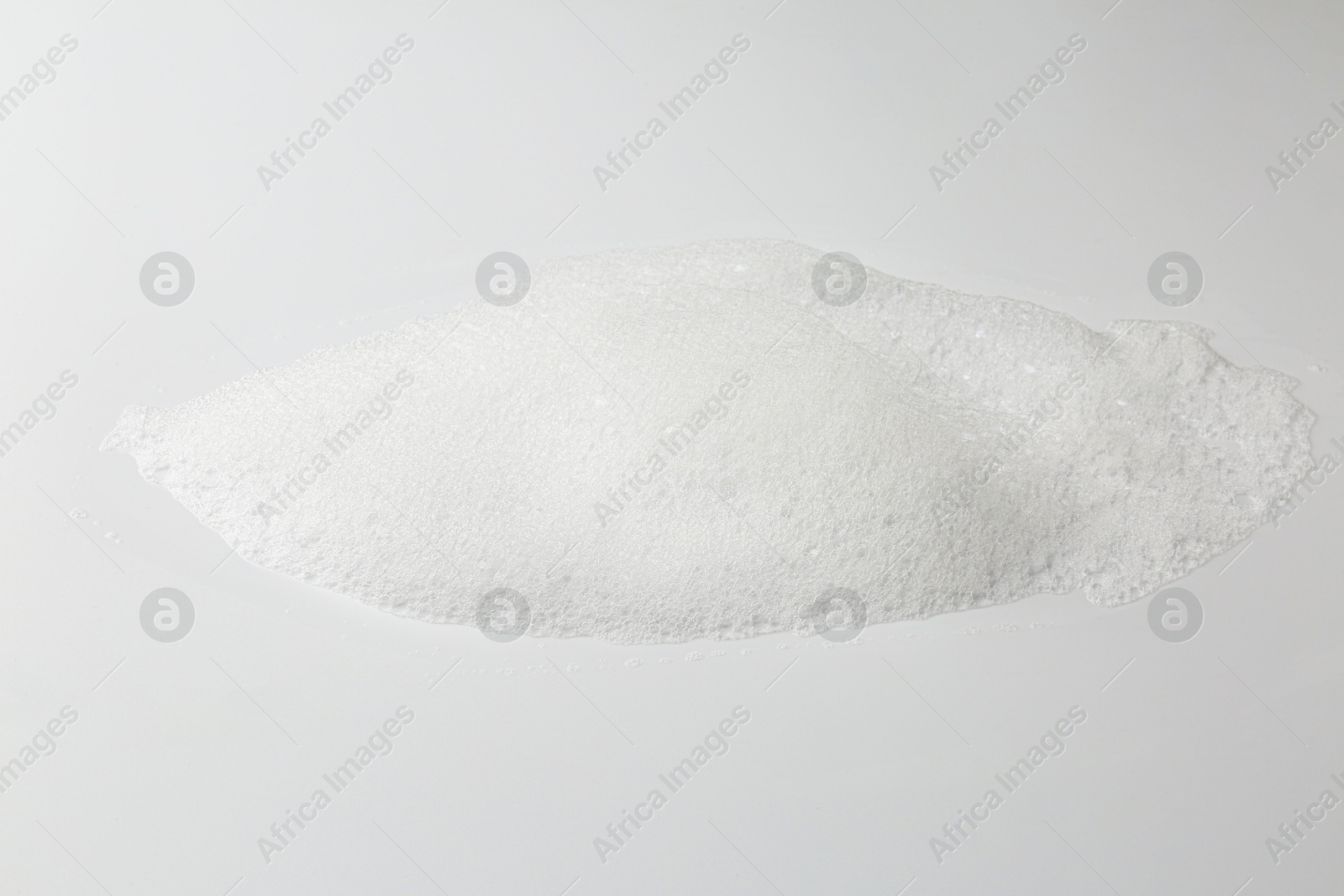 Photo of Detergent foam with bubbles on white background, closeup