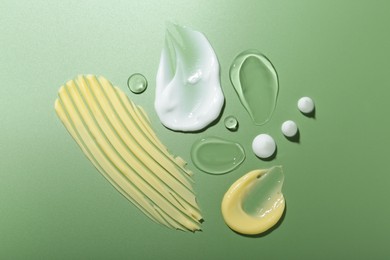 Photo of Cream and gel samples on green background, top view