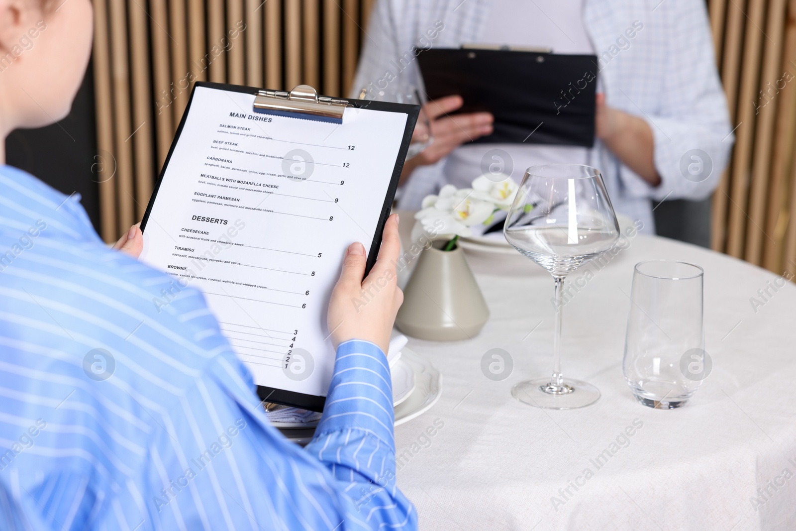 Photo of Couple choosing dishes from menu at table in restaurant, closeup