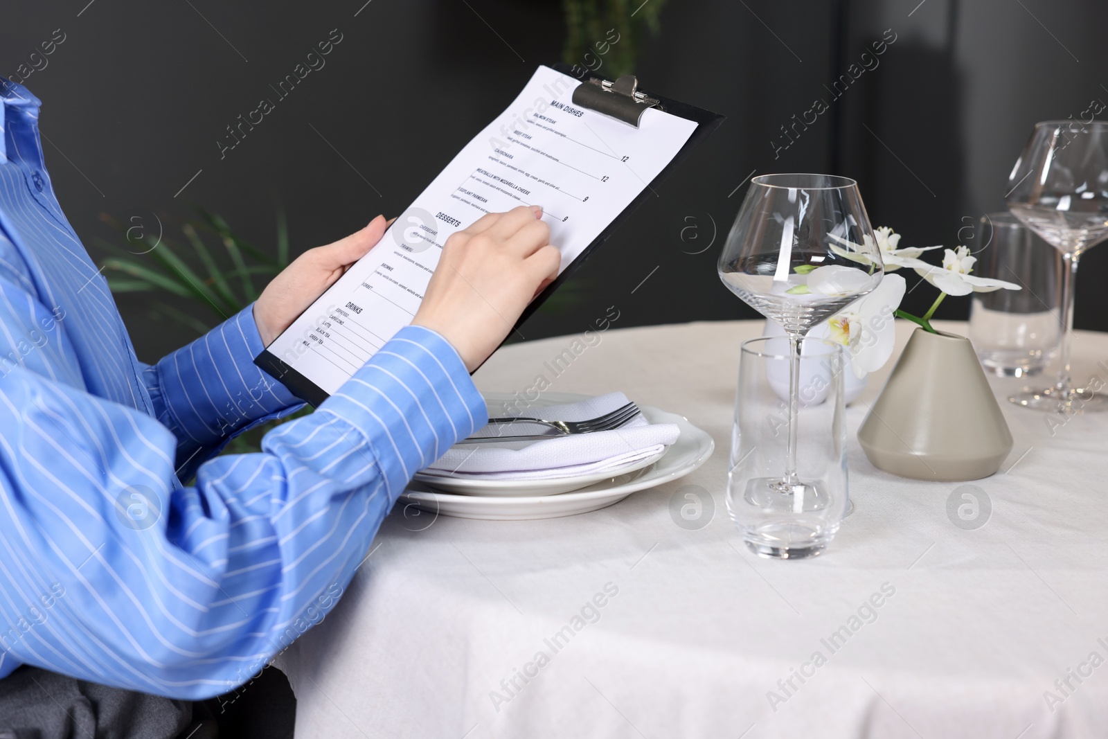 Photo of Woman choosing dish from menu at table in restaurant, closeup