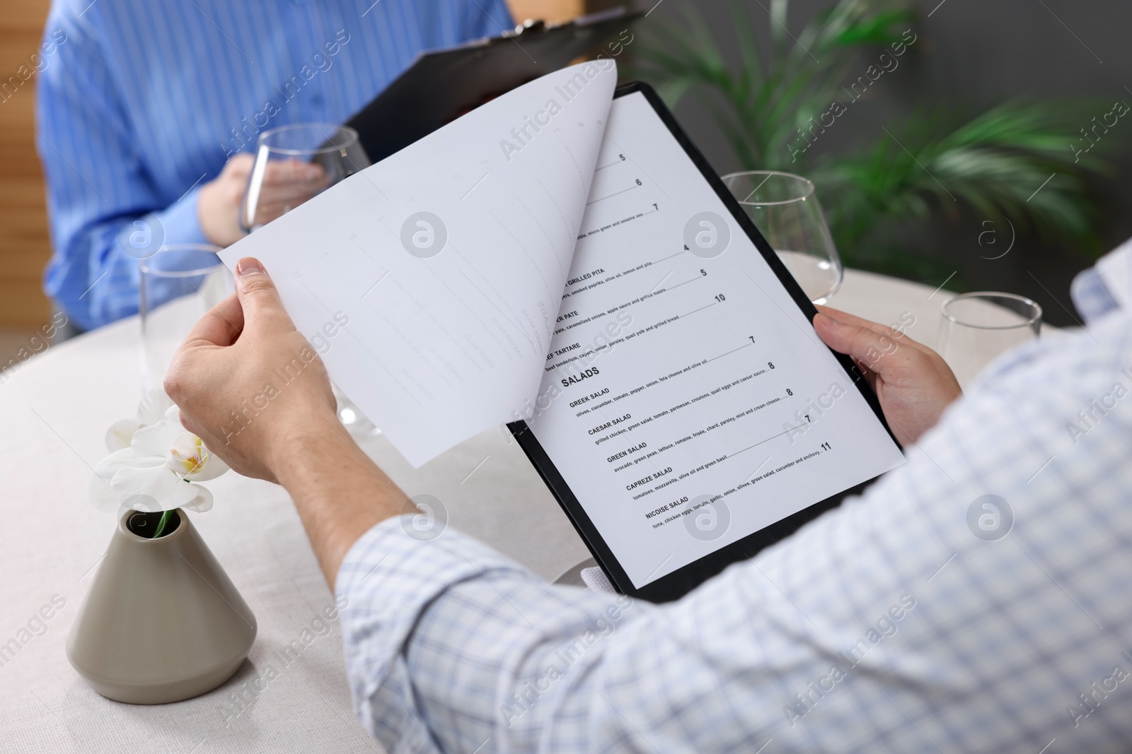 Photo of Couple choosing dishes from menu at table in restaurant, closeup