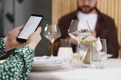 Couple choosing dishes from digital menu at restaurant, closeup