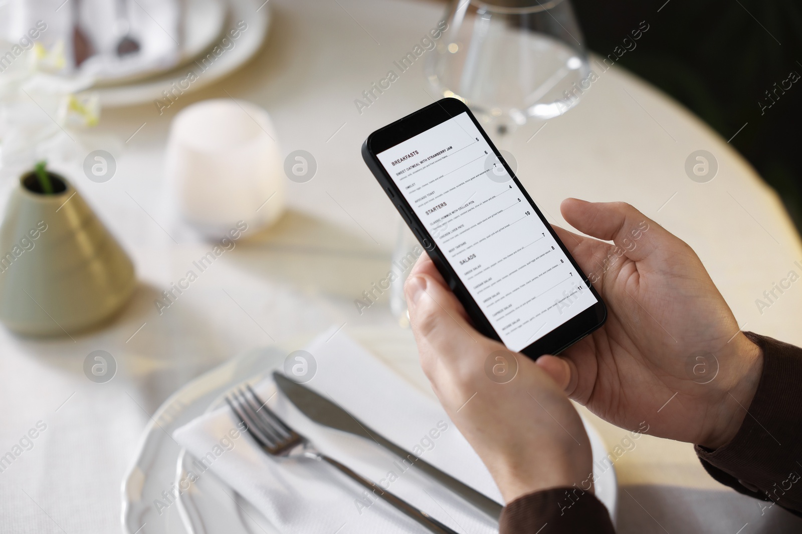 Photo of Man choosing dish from menu at table in restaurant, closeup