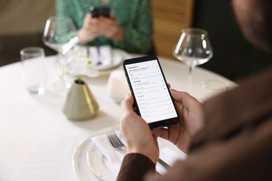 Photo of Couple choosing dishes from digital menu at restaurant, closeup