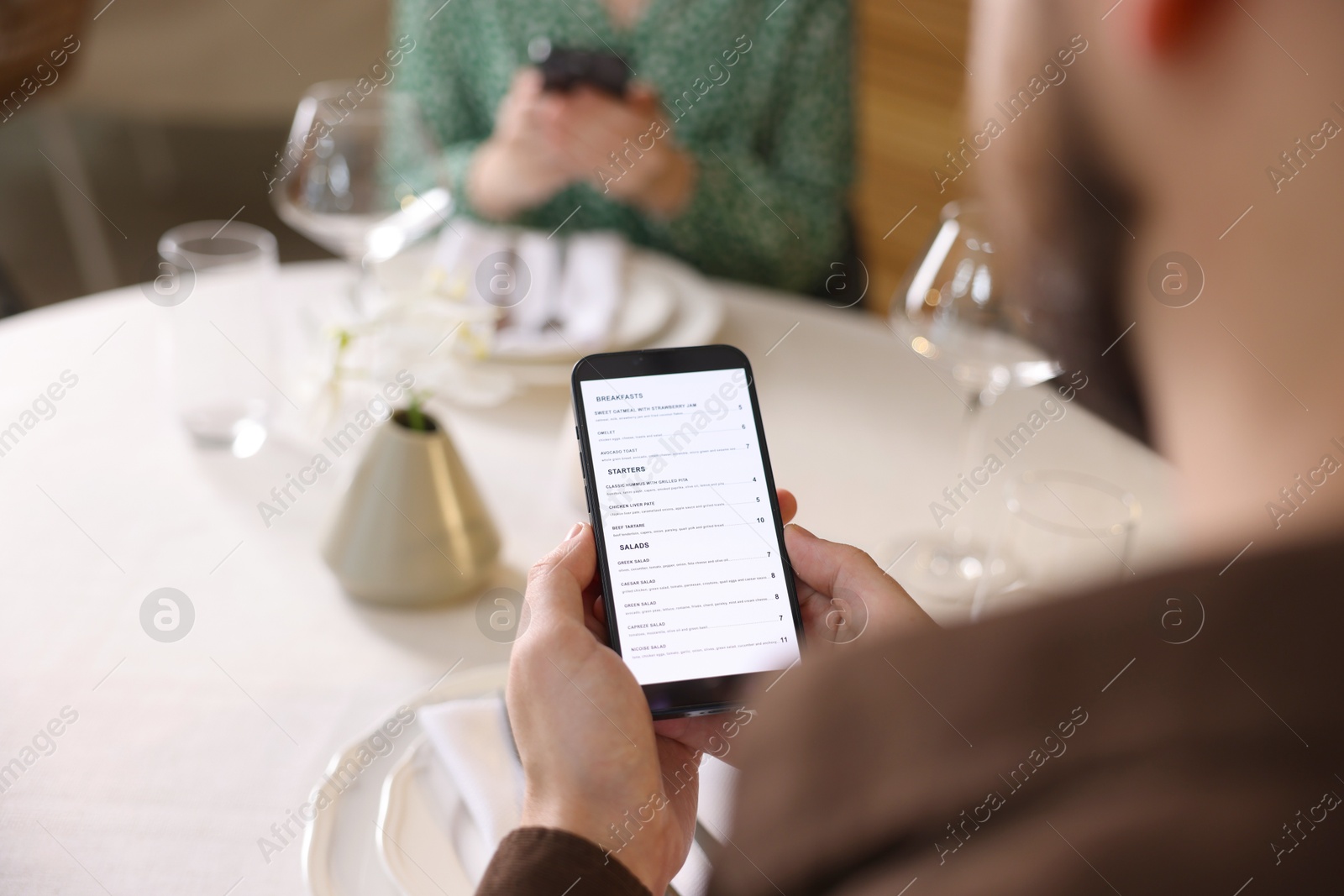 Photo of Couple choosing dishes from digital menu at restaurant, closeup