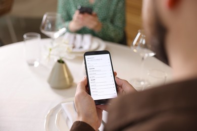 Photo of Couple choosing dishes from digital menu at restaurant, closeup