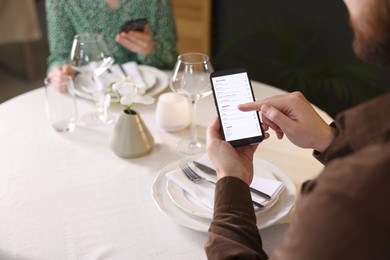 Couple choosing dishes from digital menu at restaurant, closeup