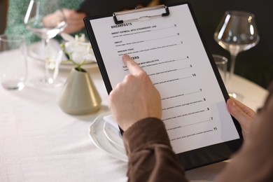 Photo of Couple choosing dishes from menu at table in restaurant, closeup