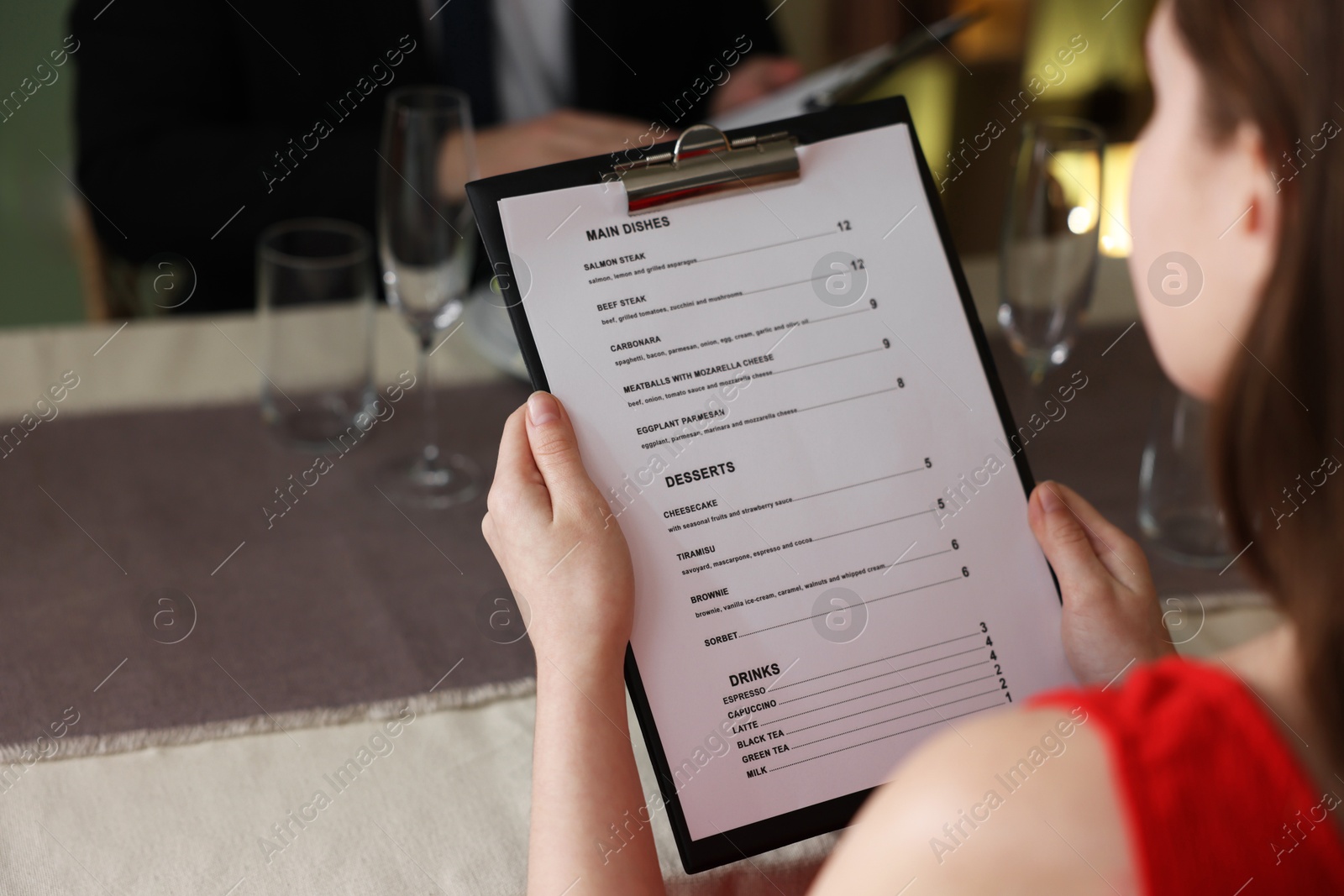 Photo of Couple choosing dishes from menu at table in restaurant, closeup