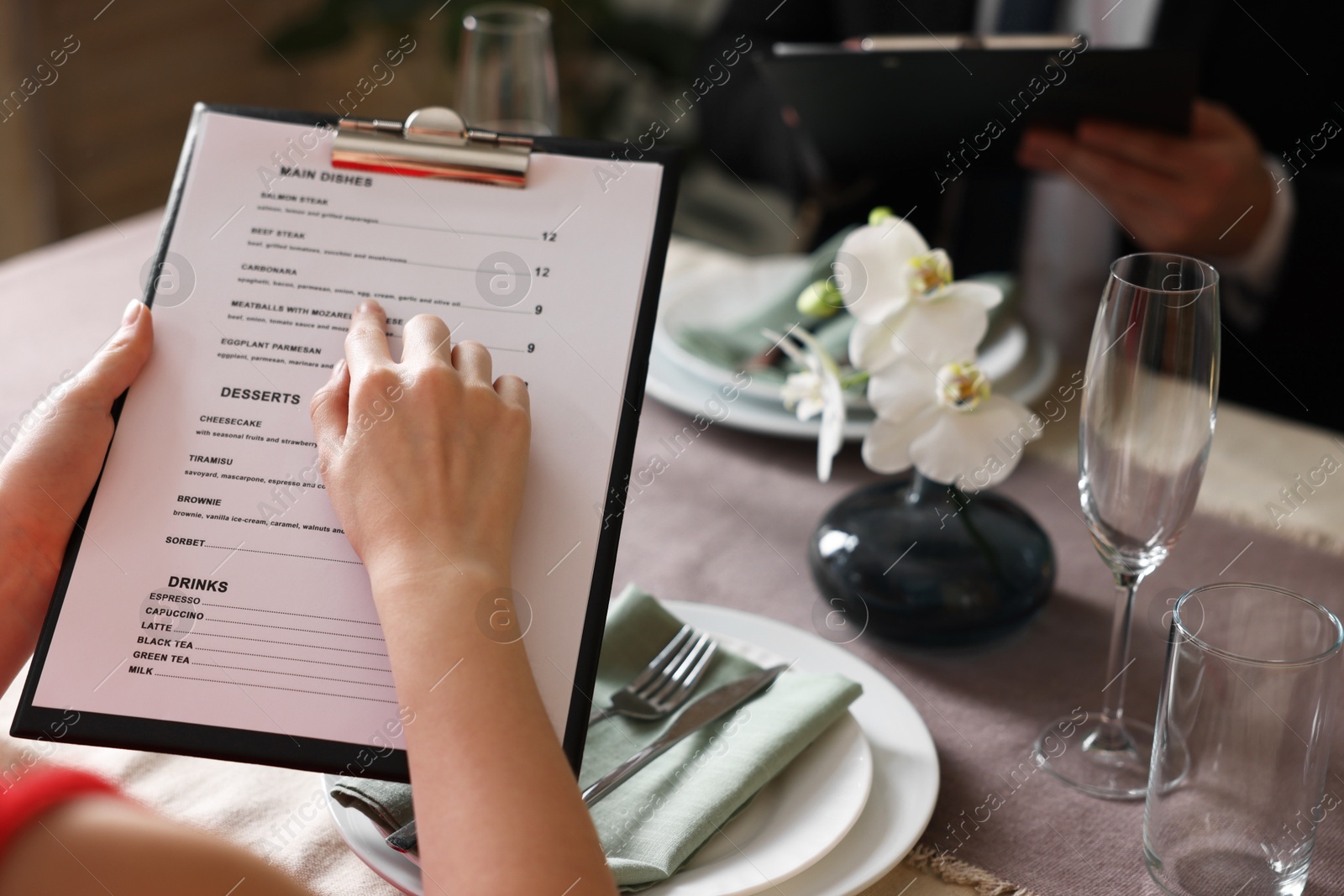 Photo of Couple choosing dishes from menu at table in restaurant, closeup