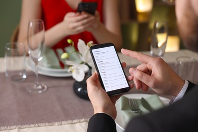 Photo of Couple choosing dishes from digital menu at restaurant, closeup