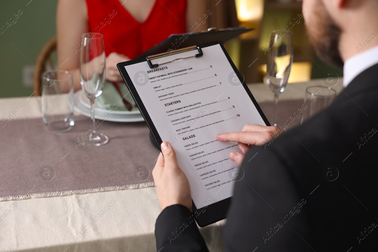 Photo of Couple choosing dishes from menu at table in restaurant, closeup