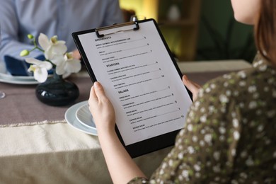 Photo of Couple choosing dishes from menu at table in restaurant, closeup