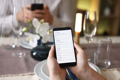 Photo of Couple choosing dishes from digital menu at restaurant, closeup