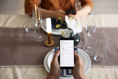 Photo of Couple choosing dishes from digital menu at restaurant, above view