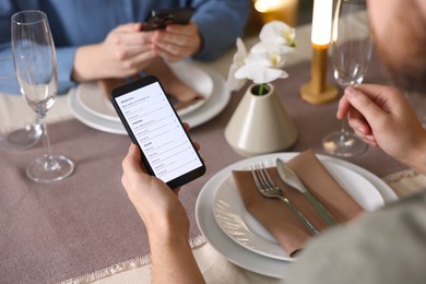 Photo of Couple choosing dishes from digital menu at restaurant, closeup