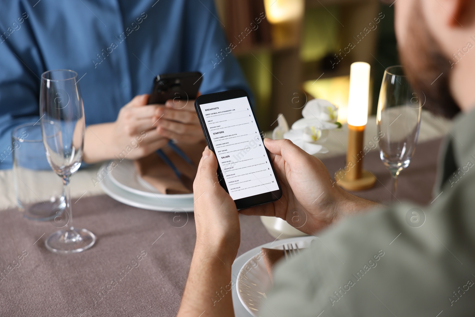 Photo of Couple choosing dishes from digital menu at restaurant, closeup