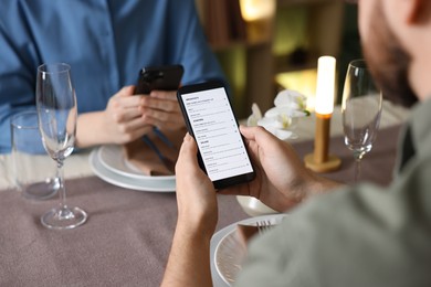 Photo of Couple choosing dishes from digital menu at restaurant, closeup