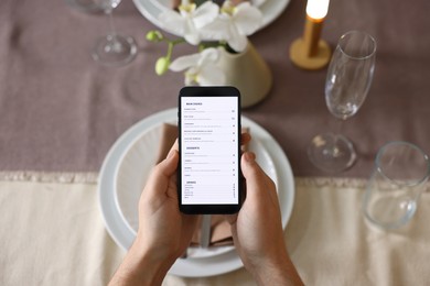 Photo of Man choosing dish from digital menu at table in restaurant, top view